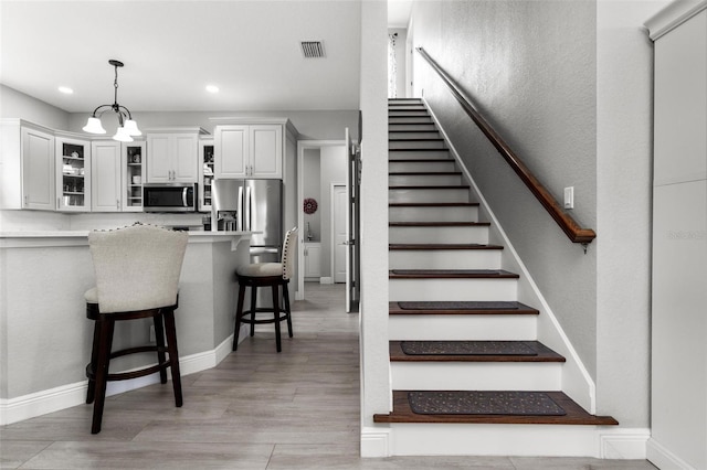 stairway with a notable chandelier and light hardwood / wood-style flooring