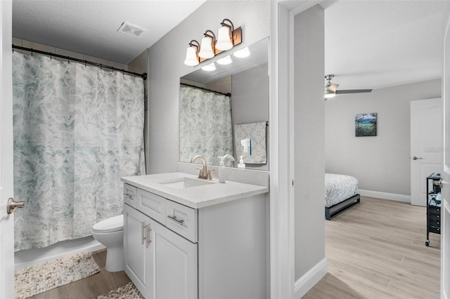 bathroom featuring toilet, large vanity, hardwood / wood-style floors, and ceiling fan