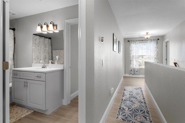 bathroom with a textured ceiling, vanity with extensive cabinet space, and hardwood / wood-style flooring