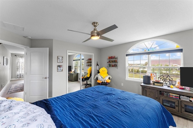 bedroom with a closet, a textured ceiling, ceiling fan, and light wood-type flooring