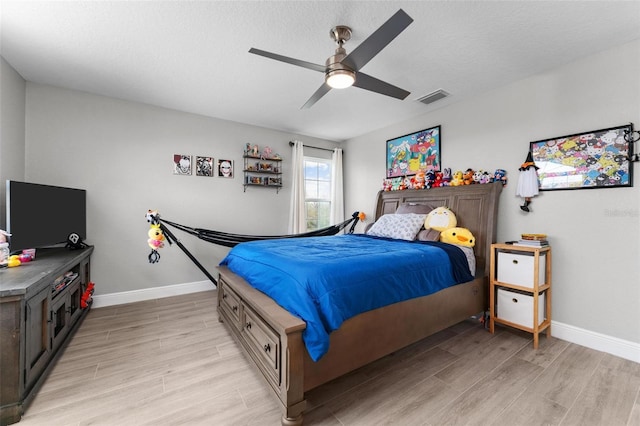 bedroom featuring ceiling fan, light hardwood / wood-style flooring, and a textured ceiling