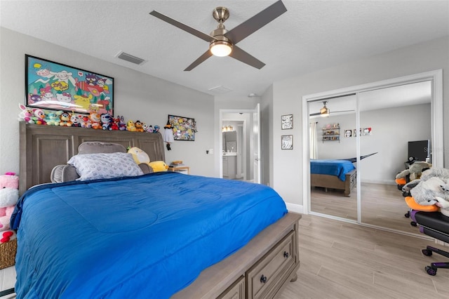 bedroom with a closet, a textured ceiling, ceiling fan, and light wood-type flooring