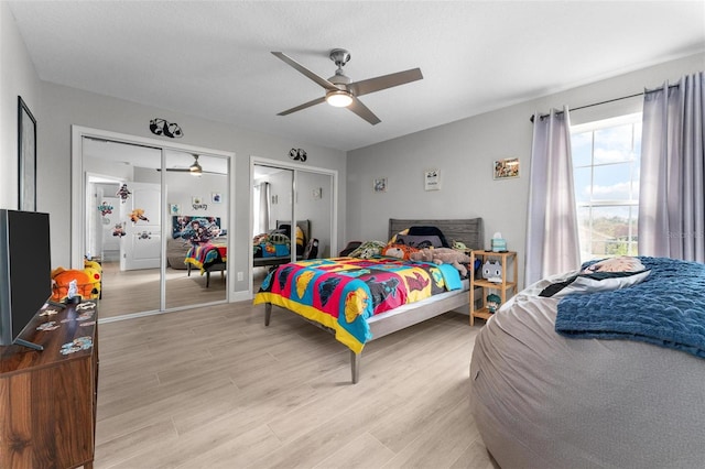 bedroom with ceiling fan, light hardwood / wood-style floors, and multiple closets