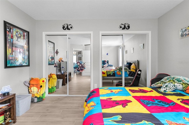 bedroom with multiple closets and light wood-type flooring