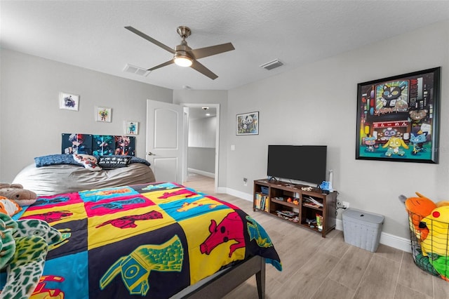 bedroom featuring light hardwood / wood-style floors, a textured ceiling, and ceiling fan