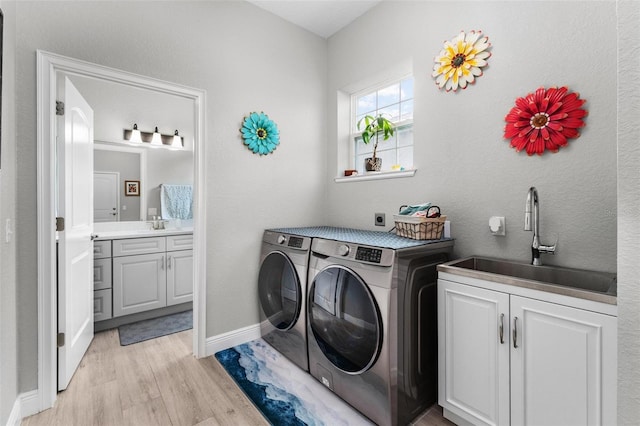 laundry area featuring separate washer and dryer, hookup for an electric dryer, cabinets, light hardwood / wood-style flooring, and sink