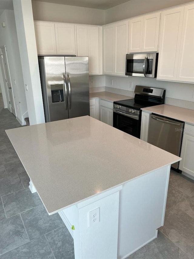 kitchen featuring stainless steel appliances, white cabinetry, light stone countertops, and tile flooring