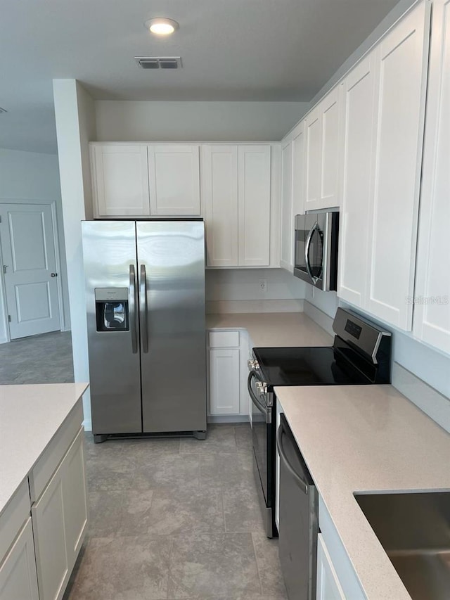 kitchen featuring stainless steel appliances, white cabinetry, and light tile floors