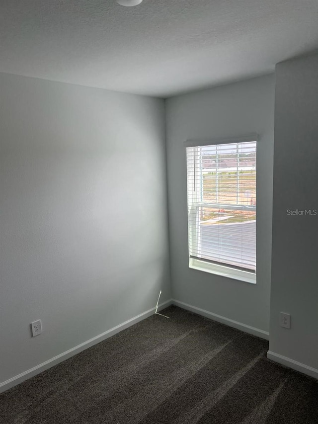 unfurnished room with dark colored carpet