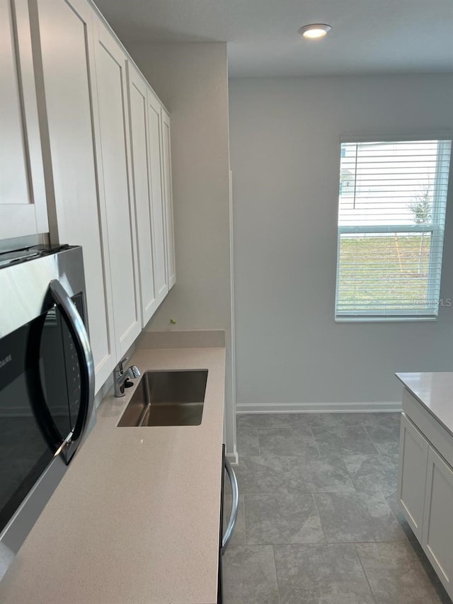 kitchen featuring white cabinetry, light tile flooring, and sink