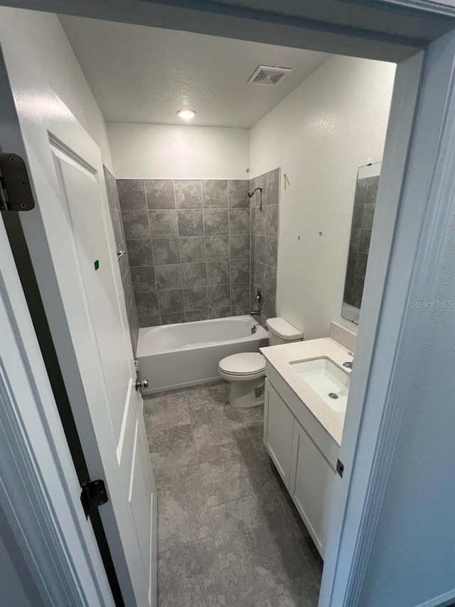 full bathroom featuring tiled shower / bath, toilet, tile floors, and vanity