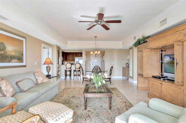 living room with light tile flooring, a tray ceiling, ornamental molding, and ceiling fan with notable chandelier