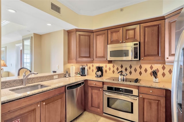 kitchen with sink, light tile floors, appliances with stainless steel finishes, light stone countertops, and tasteful backsplash