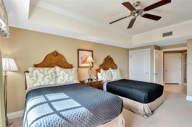 bedroom featuring ornamental molding, light colored carpet, ceiling fan, and a tray ceiling