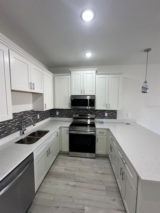 kitchen featuring decorative light fixtures, stainless steel appliances, white cabinets, and sink