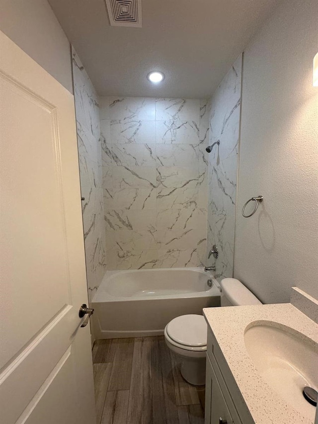 full bathroom with vanity, hardwood / wood-style floors, tiled shower / bath combo, and toilet