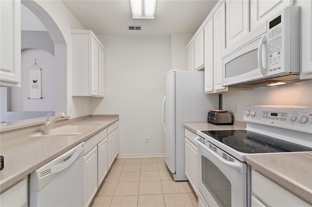 kitchen featuring white appliances, light tile flooring, white cabinetry, and sink