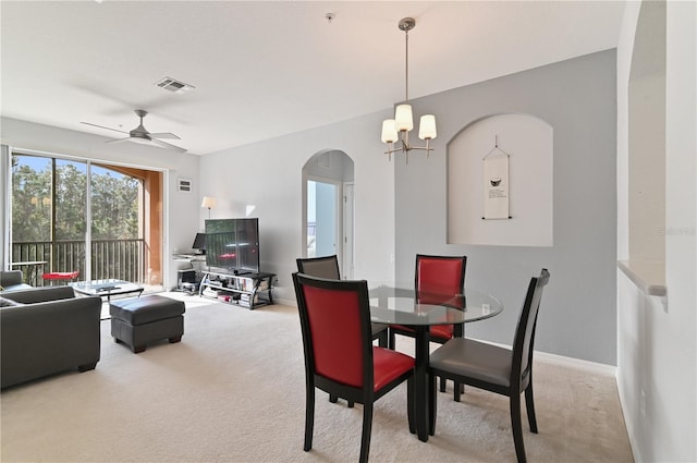 dining space featuring ceiling fan with notable chandelier and light colored carpet