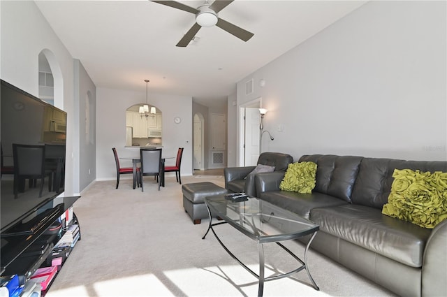 living room featuring light colored carpet and ceiling fan with notable chandelier