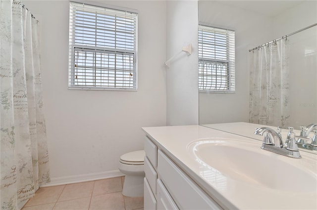 bathroom with tile floors, vanity with extensive cabinet space, toilet, and a healthy amount of sunlight