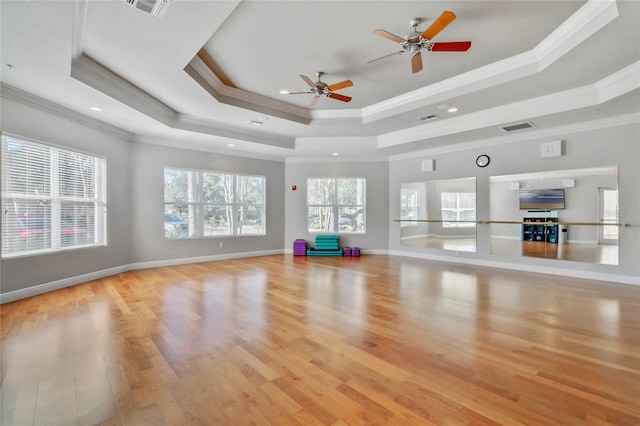 workout room featuring a raised ceiling, ceiling fan, light wood-type flooring, and crown molding