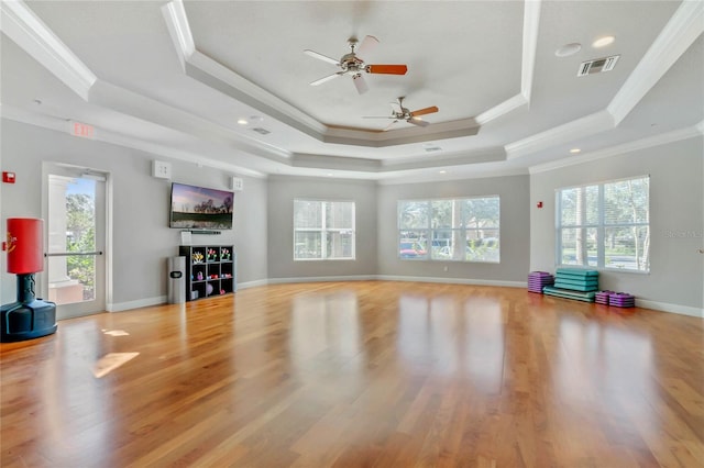 unfurnished living room featuring plenty of natural light, a tray ceiling, and light hardwood / wood-style flooring