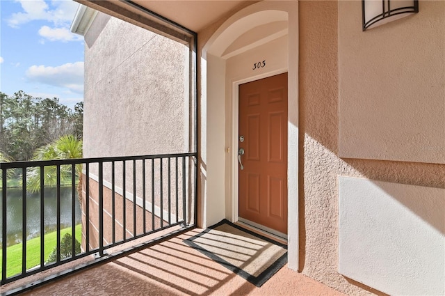 view of exterior entry featuring a balcony and a water view