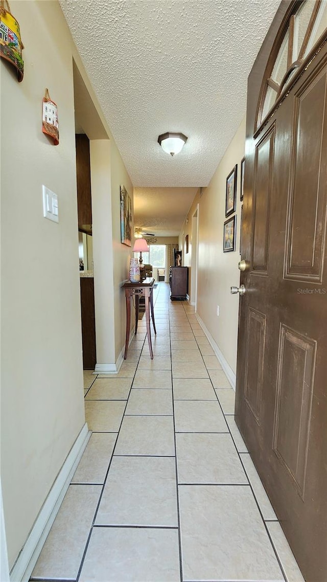 hall featuring a textured ceiling and light tile floors