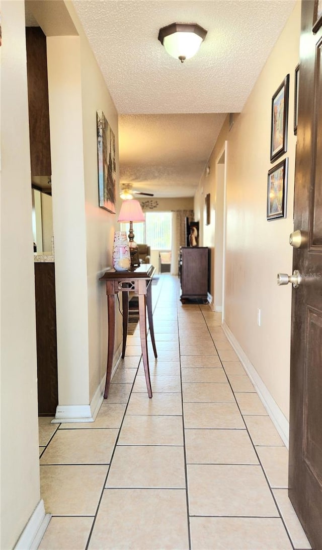 hallway with light tile flooring and a textured ceiling