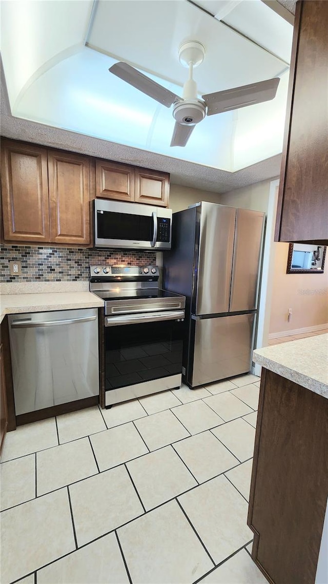 kitchen featuring tasteful backsplash, ceiling fan, appliances with stainless steel finishes, and light tile floors