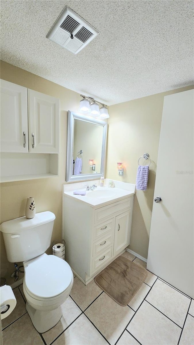 bathroom with toilet, a textured ceiling, large vanity, and tile flooring