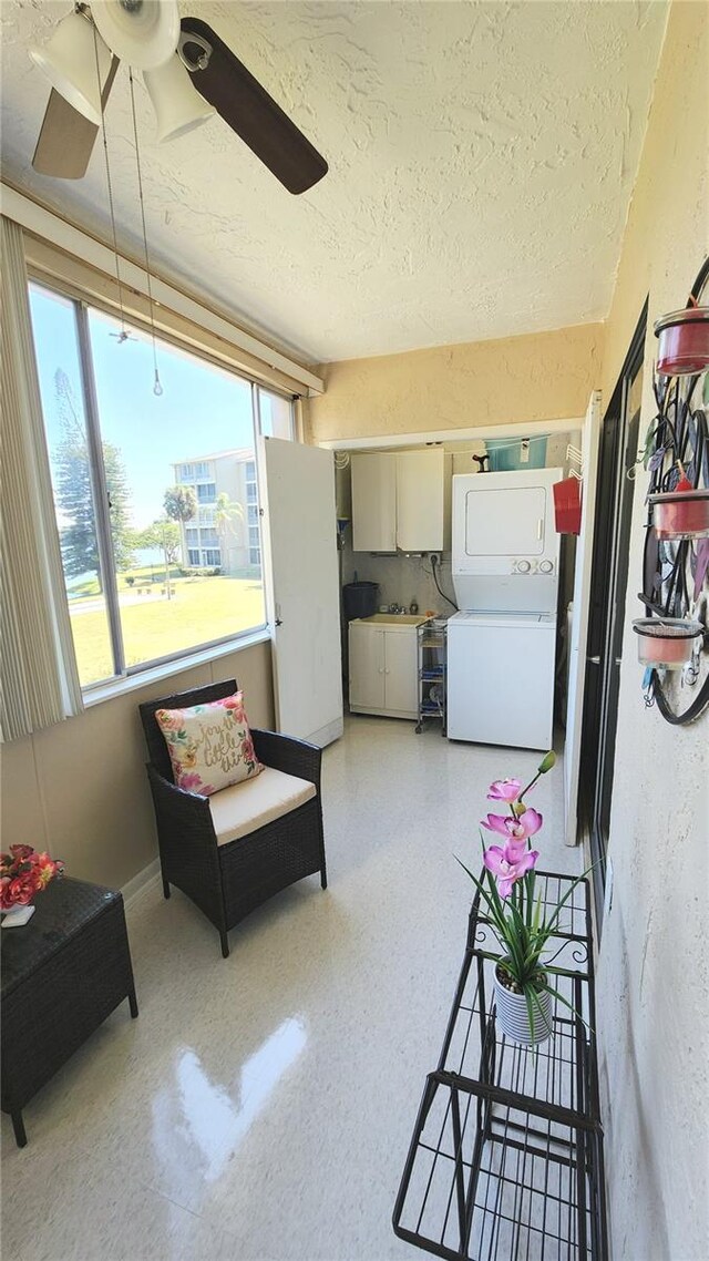 interior space with stacked washing maching and dryer, ceiling fan, and water heater