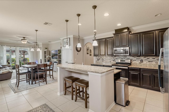 kitchen featuring stainless steel appliances, light stone countertops, ceiling fan, a kitchen island, and pendant lighting