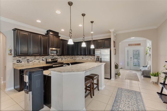 kitchen with stainless steel appliances, hanging light fixtures, a kitchen island, and tasteful backsplash