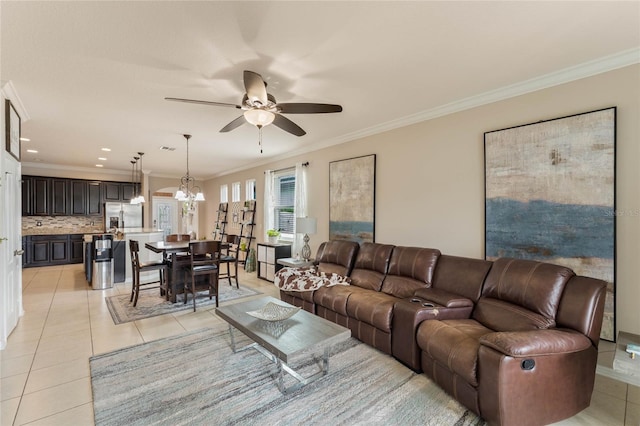 tiled living room with ceiling fan with notable chandelier and ornamental molding