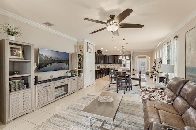 living room featuring light tile patterned floors, crown molding, and ceiling fan