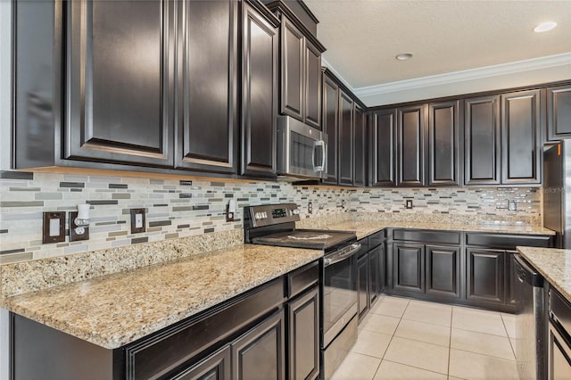 kitchen with light tile patterned flooring, light stone counters, tasteful backsplash, appliances with stainless steel finishes, and ornamental molding