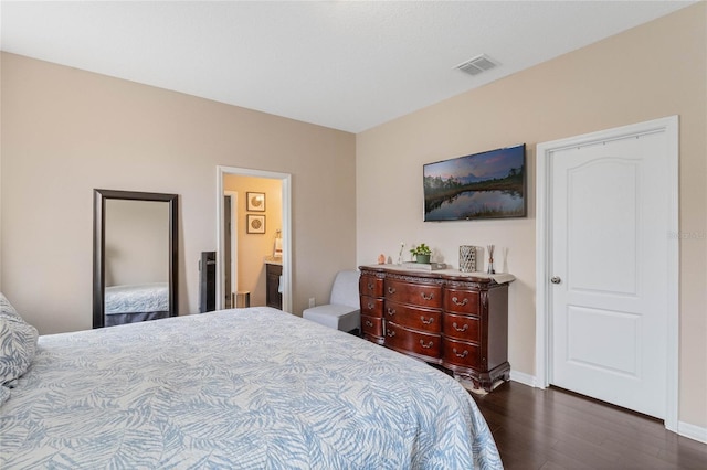 bedroom with dark wood-type flooring and connected bathroom