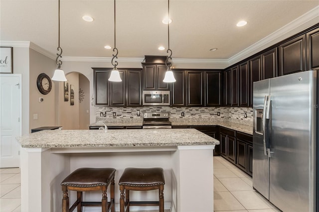 kitchen with stainless steel appliances, tasteful backsplash, a center island with sink, and decorative light fixtures