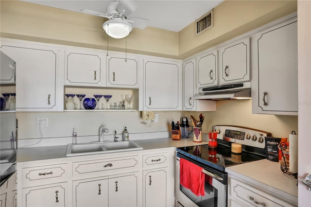 kitchen with stainless steel electric stove, white cabinetry, ceiling fan, and sink