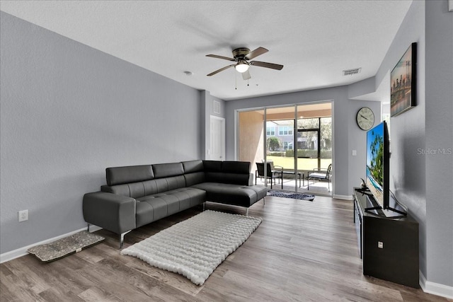 living room featuring hardwood / wood-style floors, a textured ceiling, and ceiling fan