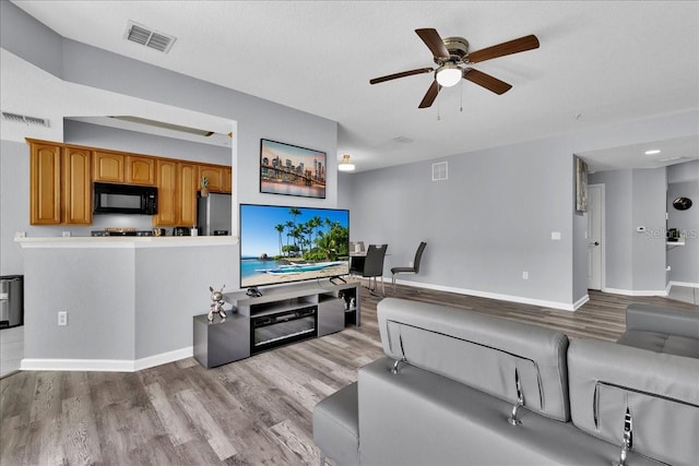 living room with ceiling fan and light hardwood / wood-style flooring