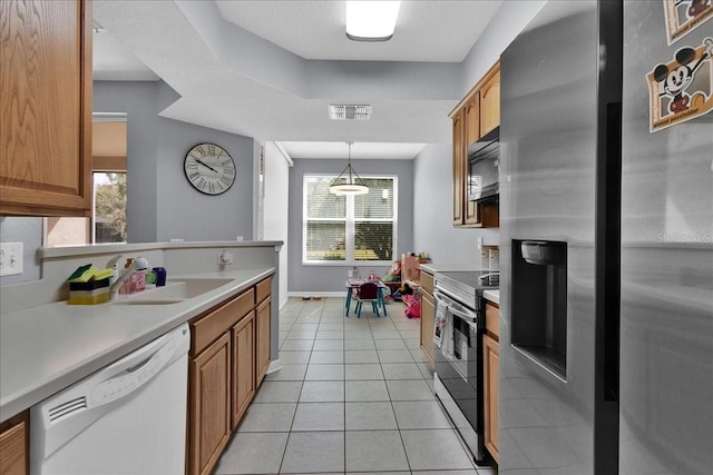 kitchen with plenty of natural light, stainless steel appliances, decorative light fixtures, and sink