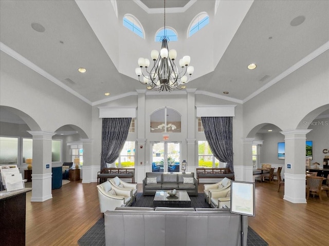 living room featuring dark hardwood / wood-style flooring, ornamental molding, a notable chandelier, and ornate columns