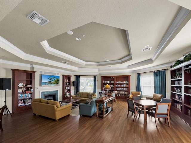 living room featuring a textured ceiling, a raised ceiling, ornamental molding, and dark hardwood / wood-style floors