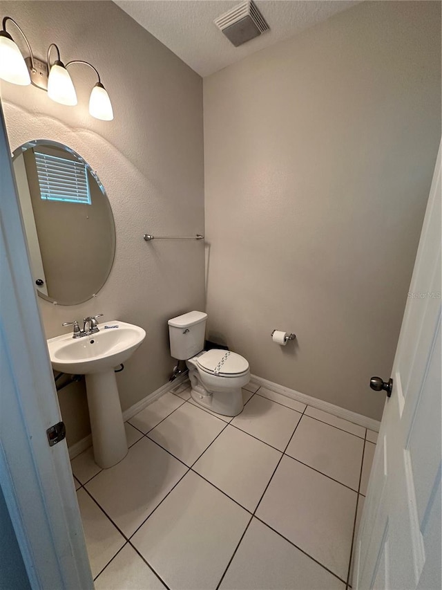 bathroom with toilet, tile flooring, and a textured ceiling