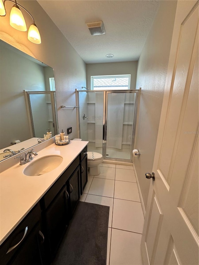 bathroom with tile flooring, a textured ceiling, oversized vanity, toilet, and a shower with shower door