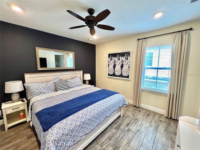 bedroom with a textured ceiling, hardwood / wood-style flooring, and ceiling fan