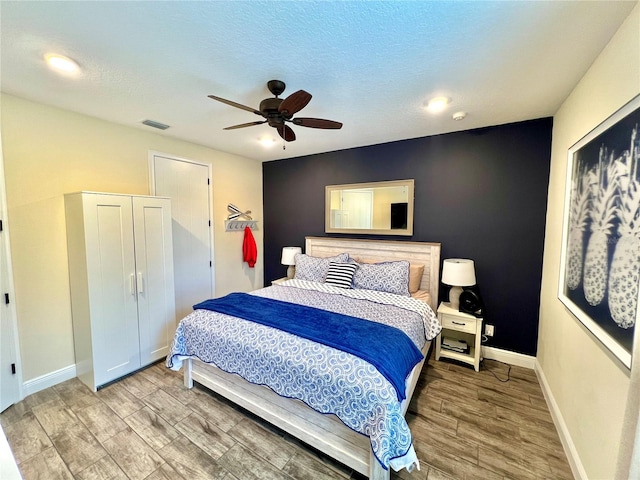 bedroom featuring hardwood / wood-style floors, ceiling fan, and a textured ceiling