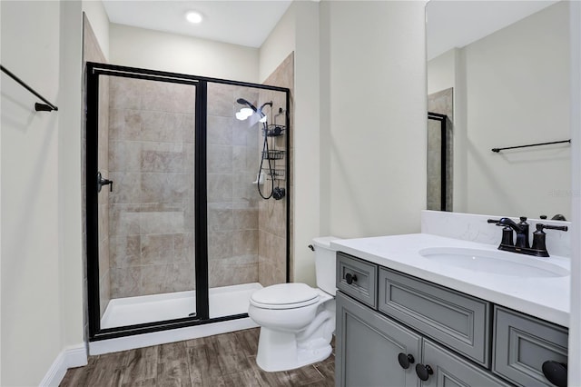 bathroom with wood-type flooring, toilet, vanity, and a shower with shower door